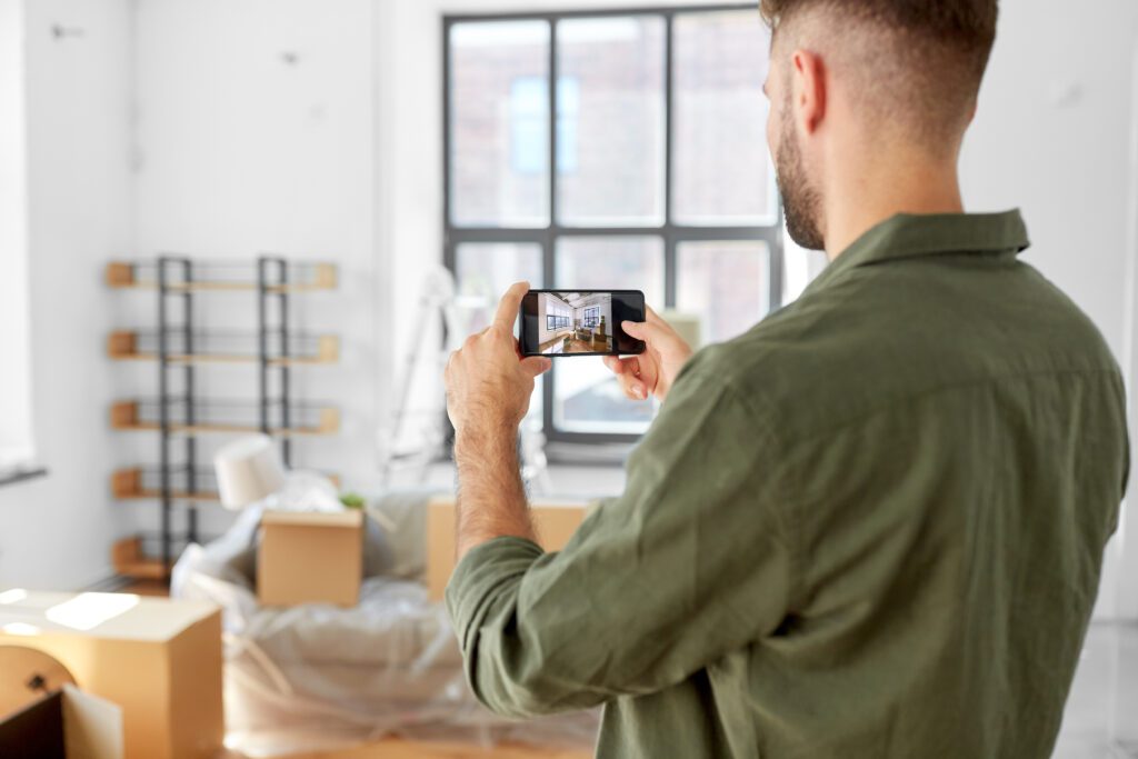 A man taking pictures of his new apartment with his smartphone.