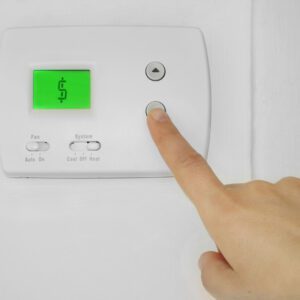 an image of a thermostat with a dollar sign on it and a hand turning the temperature down