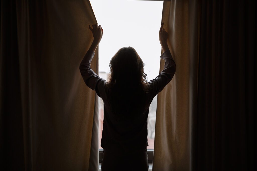 A woman's silhouette closing the curtains.
